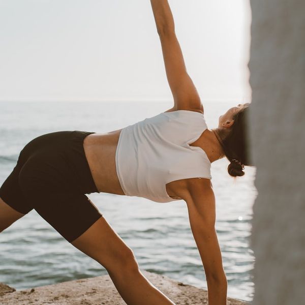 Person stretching on a yoga mat during sunrise.